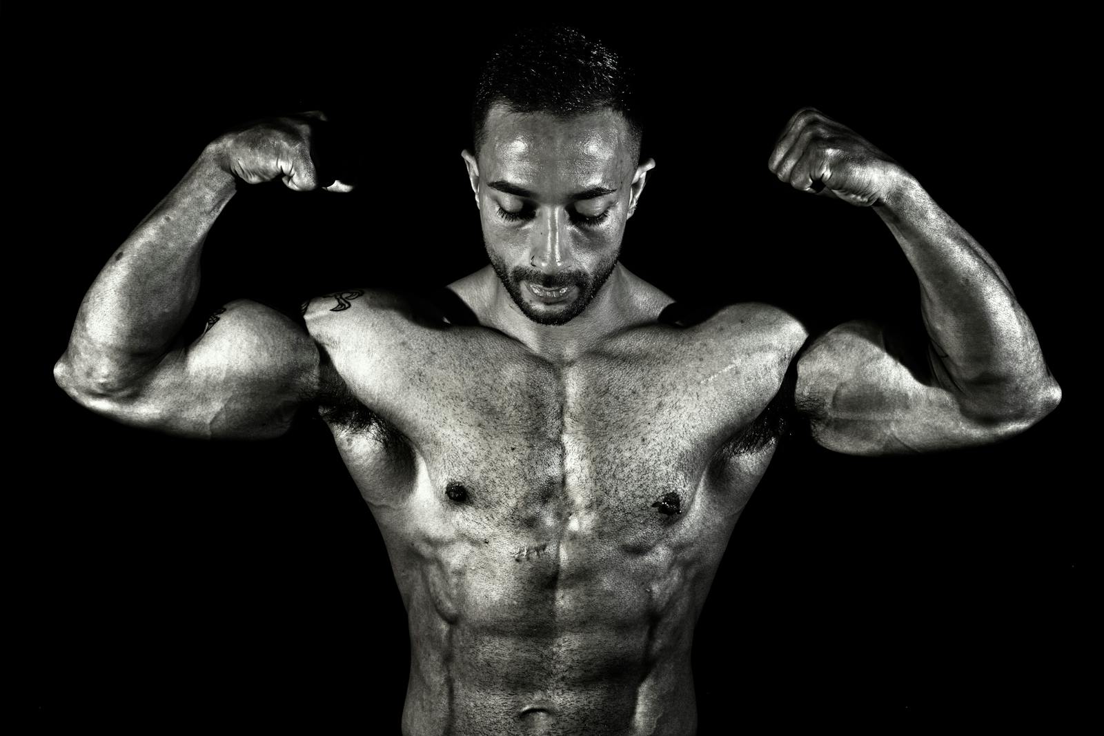 Black and white photo of a muscular male bodybuilder flexing his biceps in a dramatic pose.